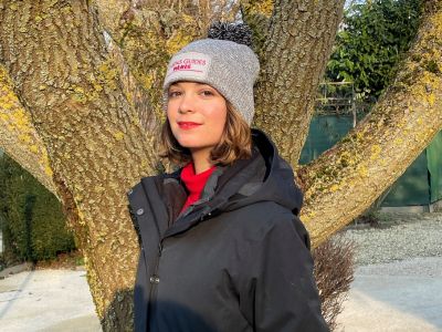 Bonnet gris clair avec pompon gris foncé , brodé avec la phrase " Chiens guides Paris " sur le devant du bonnet