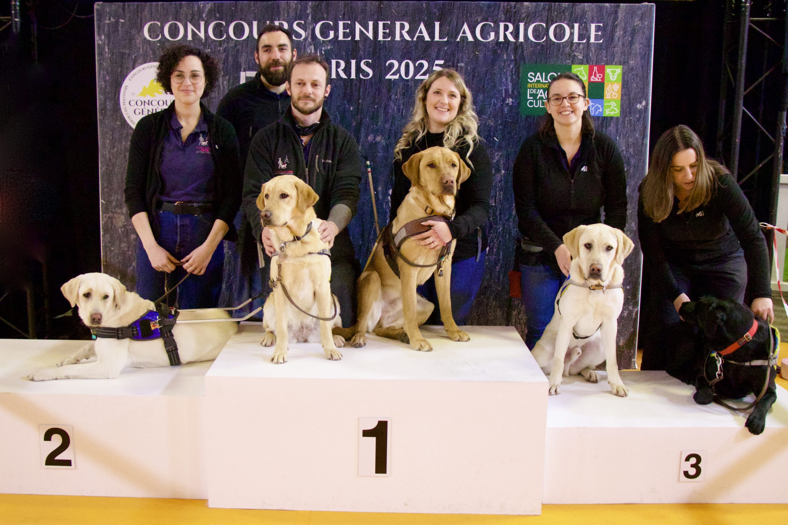 Équipes de moniteurs en éducation de l'école de Paris et du centre d'élevage de Buc au Salon de l'Agriculture 2025. La photo a été prise avec les chiens sur le podium.