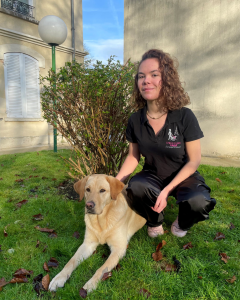 Photo de Charlotte, alternante en communication avec un labrador beige allongé a coté d'elle