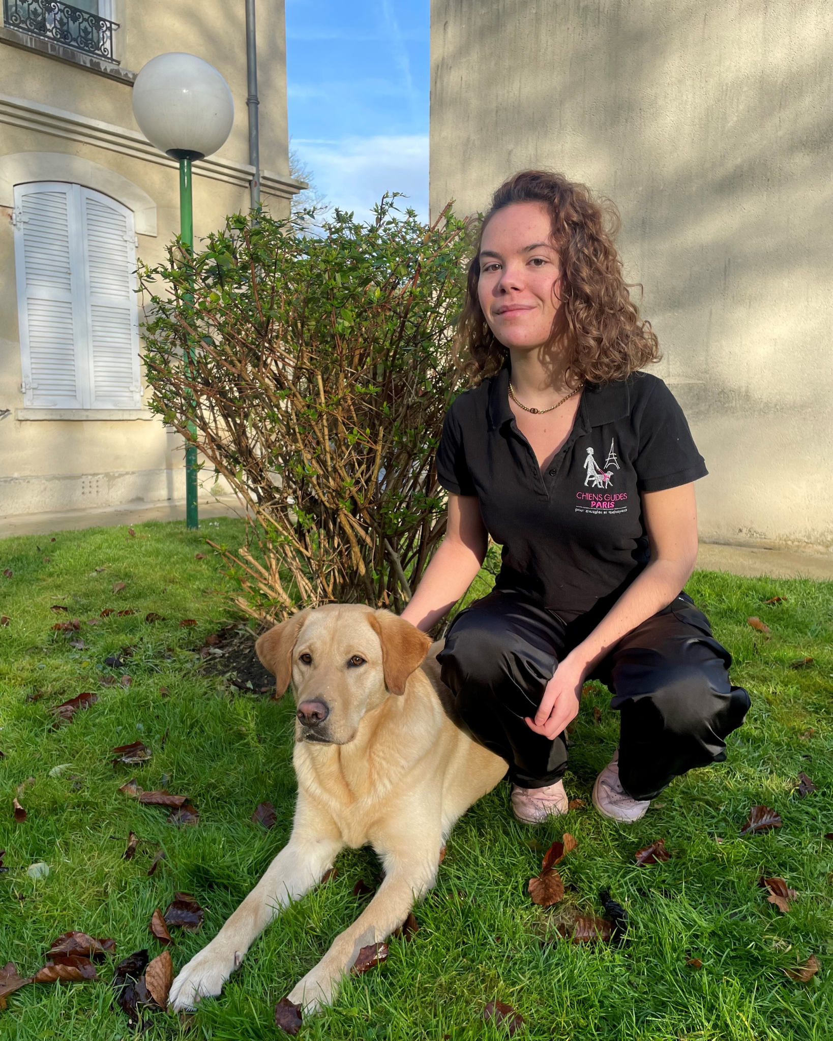 Photo de Charlotte, alternante en communication  avec un labrador beige allongé a coté d'elle 