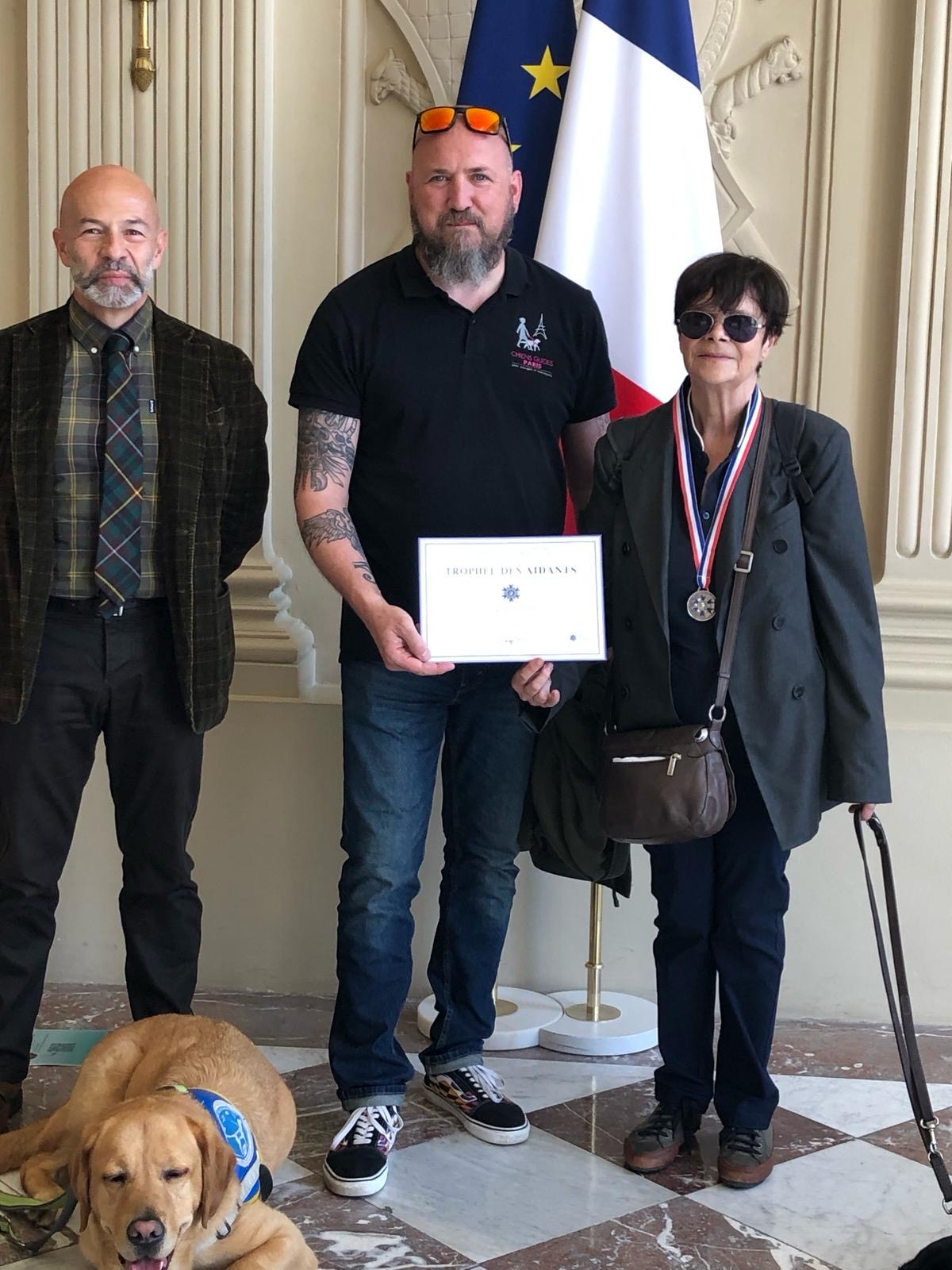 Photo de groupe à l’Assemblée Générale avec William, directeur de Buc, tenant dans ses mains le diplôme du "Trophée des Aidants 2025". À sa droite, Dominique, vice-présidente et trésorière de l’association.